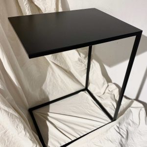 Mesa Auxiliar metálica de color negro Otter ambientada sobre tela