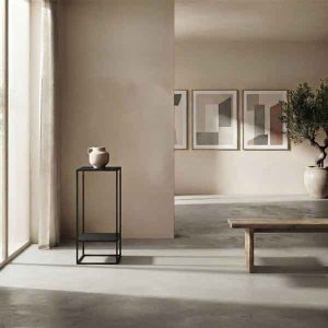 Pedestal Plinto Ruan negro junto a una ventana y una banca baja